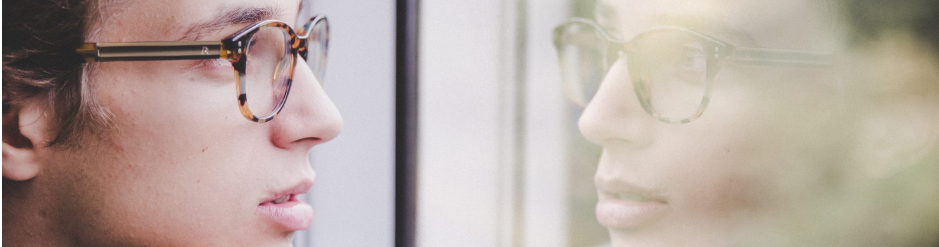 Self-awareness; a man looking at his reflection in a window